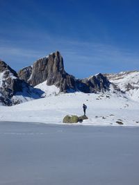 Man on snowcapped mountain against blue sky