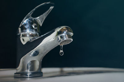 Close-up of water faucet against black background