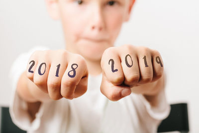 Close-up portrait of boy showing numbers on hands