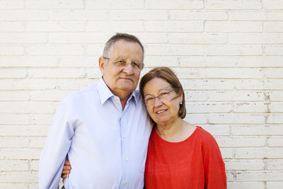 Portrait of senior couple in front of white brick wall