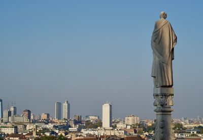 Statue in city against clear sky