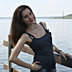 Portrait of beautiful woman leaning on railing against sea