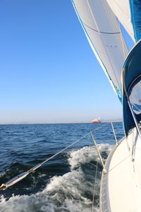 Sailboat sailing in sea against clear blue sky