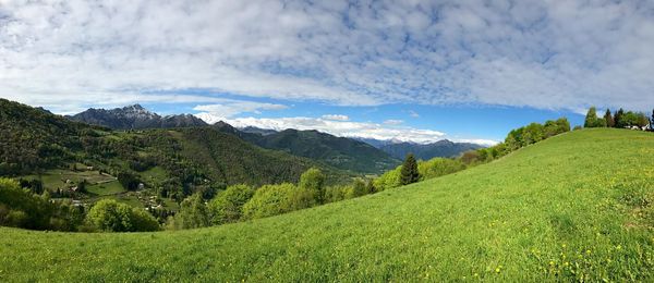 Scenic view of green landscape and mountains against sky