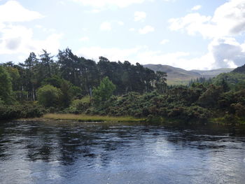 Scenic view of river and mountains against sky