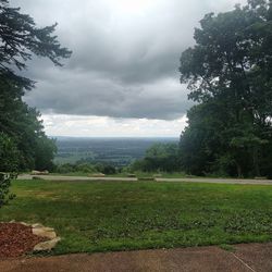 Trees on field against cloudy sky