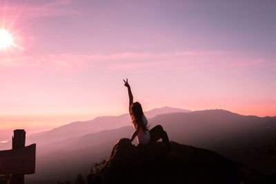 Man climbing on mountain against sky during sunset