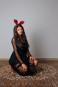Portrait of young woman sitting against wall