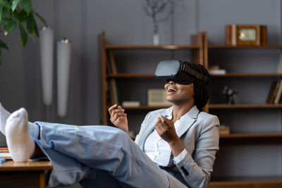 Impressed african american woman remote employee using vr headset to relax after hard working day