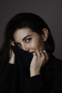 Portrait of young woman against black background