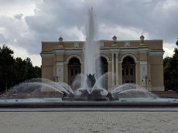 Fountain in city against sky