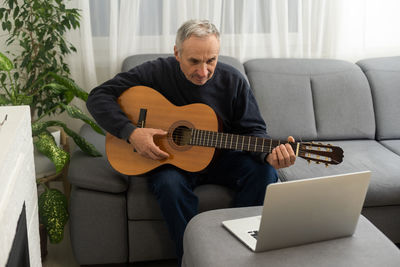 Man using laptop while sitting on sofa at home