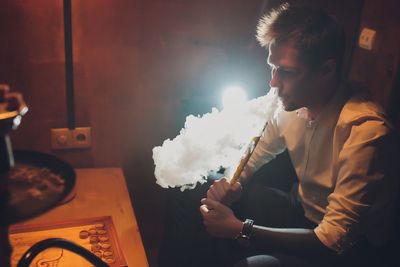 Young man smoking hookah at home