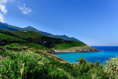 Scenic view of sea and mountains against blue sky