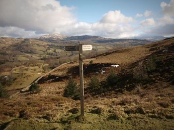 Scenic view of sign post in field against sky