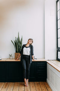 Girl in a business suit and glasses stands working near the window at home, in the office