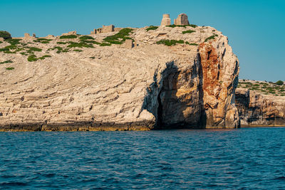 Shadow of rocks on rock by sea against clear sky