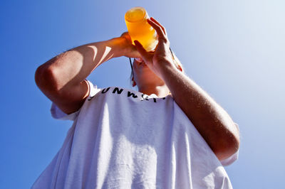 Low angle view of woman drinking drink against clear sky