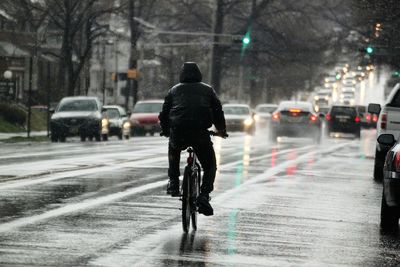 Rear view of man riding bicycle on road in winter