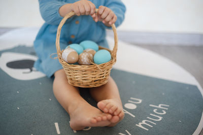 Low section of kid holding easter eggs in basket