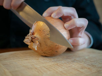 Close-up of hand holding bread on cutting board