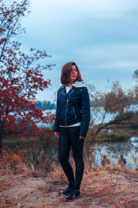 Young woman looking away while standing on land against sky