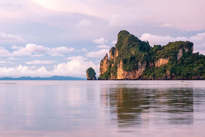 Scenic view of sea by mountain against sky