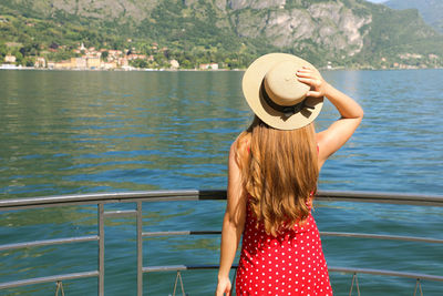 Rear view of woman standing by lake