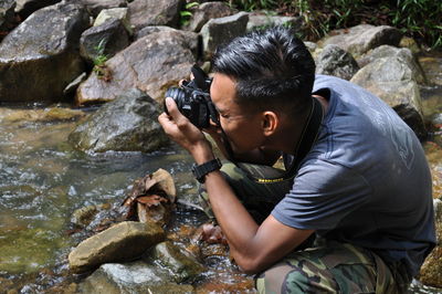 Side view of man holding rock in water