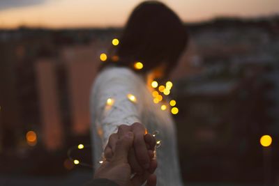 Close-up of woman holding illuminated lights at night