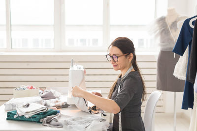 Side view of smiling tailor working at boutique