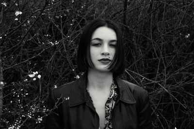 Portrait of beautiful young woman against trees