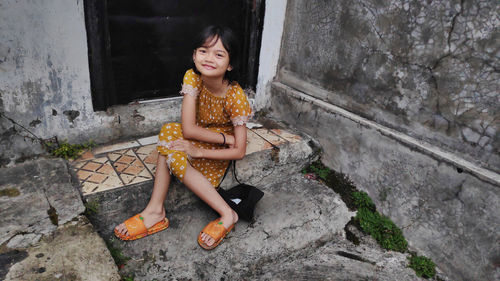 Full length of young woman standing against wall