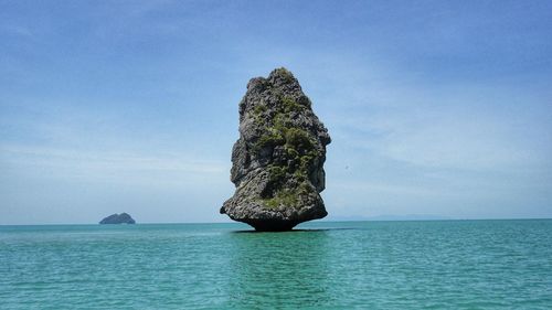 Rock formation in sea against blue sky