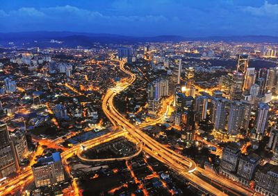High angle view of illuminated street amidst buildings in city at night