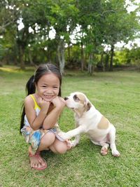 Portrait of smiling girl crouching by puppy on land in park