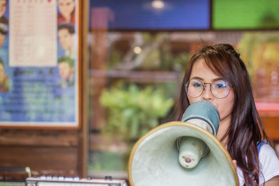 Young woman looking away while holding megaphone