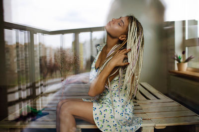 Portrait of smiling young woman sitting on chair at home