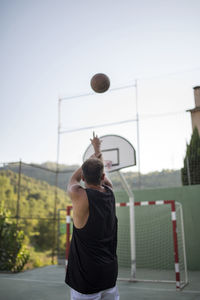 Rear view of man playing basketball against clear sky