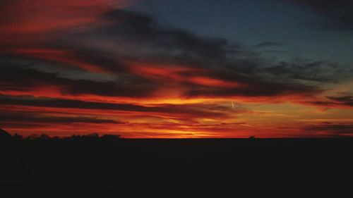 Scenic view of dramatic sky over silhouette landscape