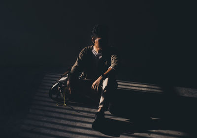 Young man sitting in the dark