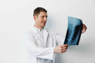 Portrait of young man holding key against white background