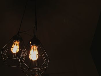 Low angle view of illuminated light bulbs hanging indoors