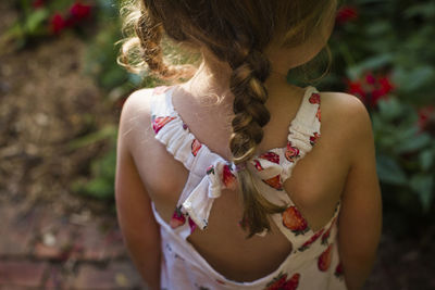Rear view of girl with braided hair standing in backyard