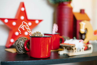 Red metal mug with tea and candy cane with christmas decor