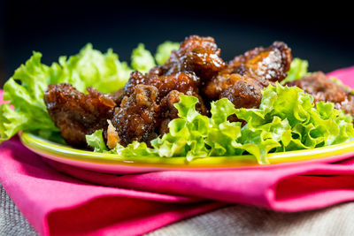 Close-up of chicken with lettuce served in plate against black background