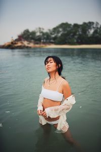 Sensuous young woman wearing bikini standing in sea