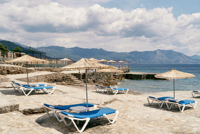 Deck chairs on beach against sky