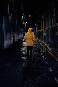 Rear view of man walking on street at night