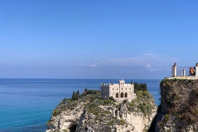 Buildings by sea against blue sky